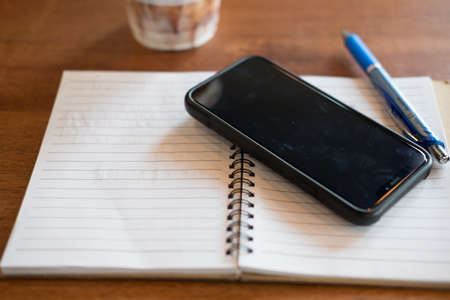 Office desk with cup of iced coffee phone on notebook. Freelancer conceptの写真素材