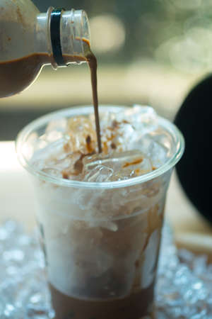 Pouring coffee into glass with ice (creativity for customer fun)