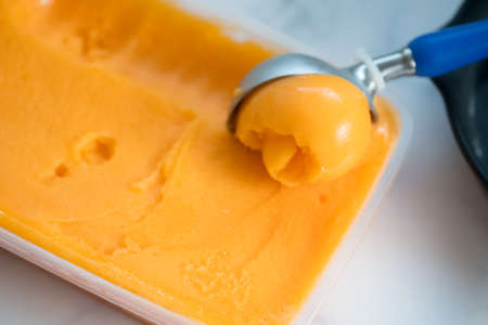 Scoop of passion fruit flavor ice cream in box on marble backgroundの写真素材