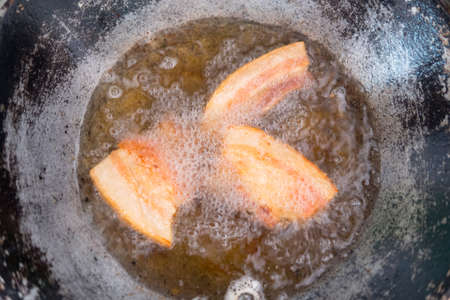 Frying pork belly in hot oil in panの写真素材