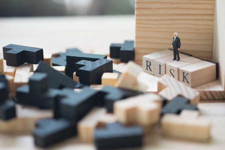 Miniature people : businessman standing on a wood cube word with risk. Business risk assessment or management conceptの写真素材