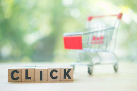 Wooden blocks with click and small shopping cart. Concept of online shopping application on a screen.の写真素材