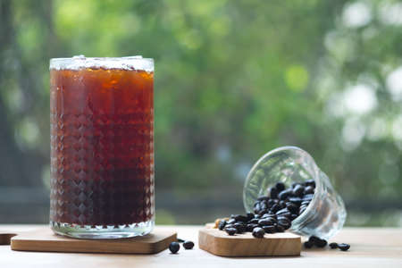 Cold brewed iced coffee in tall glass with coffee beans with nature backgroundの写真素材