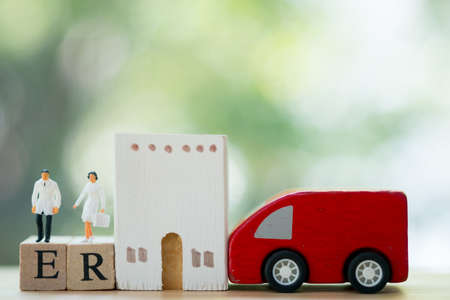 Miniature people: Doctor and nurse standing on wooden block with words ER, car and hospital. Concept of prepared emergency in long holidayの写真素材