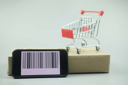 Smartphone with barcode on screen with shopping cart on brown box. Concept of online shopping, E commerce and delivery of goods.の写真素材