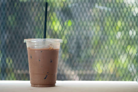 Glass of ice cocoa with drinking straw on wood table. Drink in the morningの写真素材