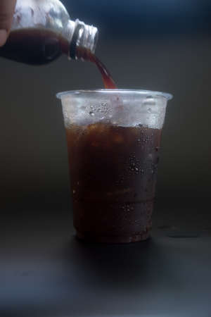 Closeup image of pouring coffee into a glass with ice cubeの写真素材