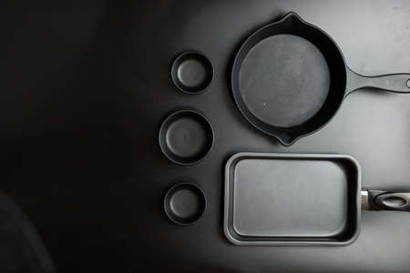 Different sizes black cook pan and black different sizes bowl on black table top. View from above.の写真素材