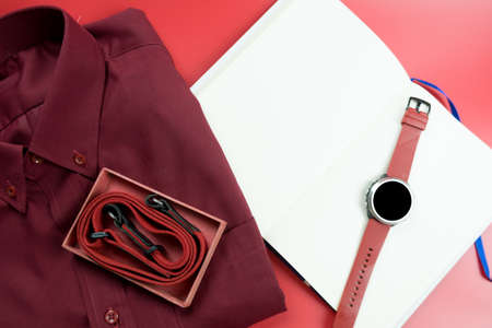 Red theme with shirt, smart watch and mini paper notebook on red backgroundの写真素材
