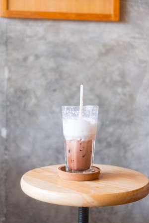 Glass of ice cocoa with  milk foam after finished drinking on wooden tableの写真素材