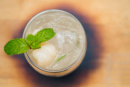 Iced drink lychee mix soda with lychee fruit and mint decoration in glass
