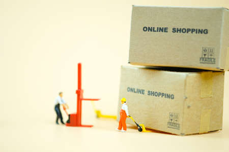Miniature warehouse worker pulling a pallet truck with brown boxes prepare for transport order from online shopping. online shopping conceptの写真素材
