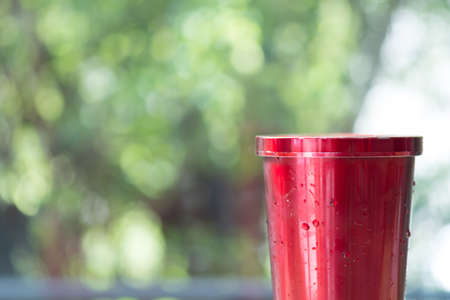 Red stainless steel tumbler for keeping of the drink cold or hot with nature background. Concept of reduce plastic pollution.の写真素材