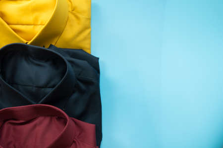 Folded male fashion shirts for adult collection on blue background. Copy space for text.の写真素材
