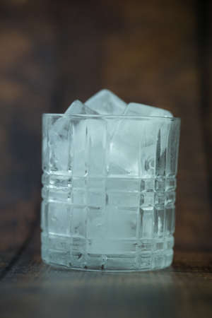 A transparent glass with ice on wood background