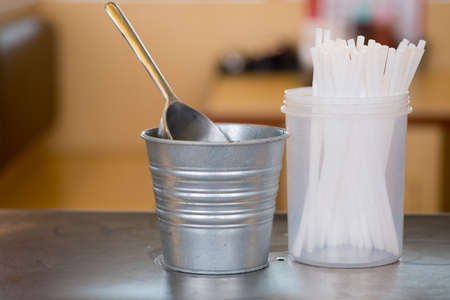 Stainless ice scoop in stainless tang and drinking straws in buffet restaurant