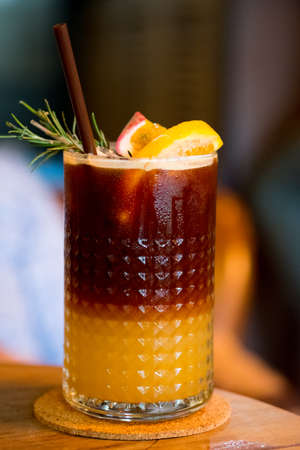Shot of coffee mix with juice (passion fruit and orange) in glass. Summer drink decoration with orange slice and passionfruit sliceの写真素材
