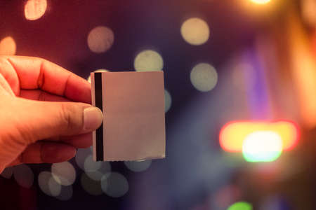 Hand holding a paper ticket on blurred background (booking ticket concept)の写真素材
