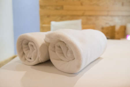 Close up roll of white towel on bedの写真素材