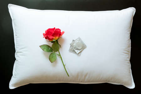 Condom and red rose on white pillow. Concept of birth Controlの写真素材