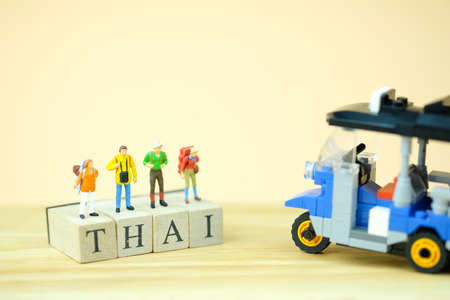 Miniature tourist standing on wooden word is THAI near Tuk tuk Thailand traditional taxiの写真素材