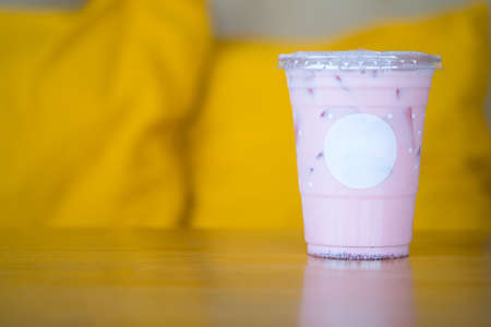 Iced pink fresh milk in plastic cup on sofa at coffee shopの写真素材
