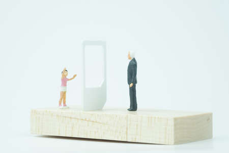 Miniature people. Father having video call with son on mobile phone. Communication and family conceptの写真素材