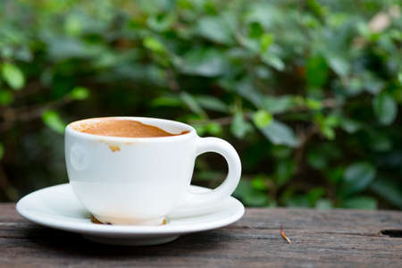 Empty hot coffee cup after drink on wood table with nature background