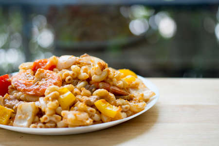 Penne pasta with shrimps in white dish on wood table