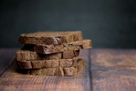 Sliced dark brown bread made of rye and wheat flour on wood table