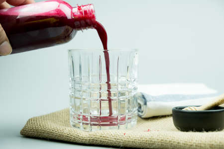 Pouring beetroot juice mix with ginger and lemon from bottle. Drink for colon cleansing