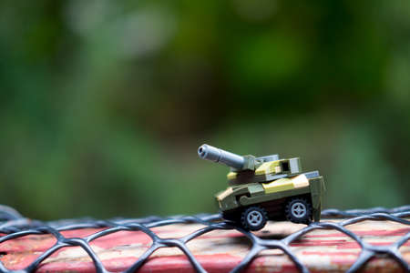 Miniature toys plastic tank on nature background. Concept of sample picture of war scenario