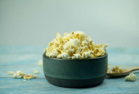 Popcorn in a bowl against blue wooden backgroundの写真素材