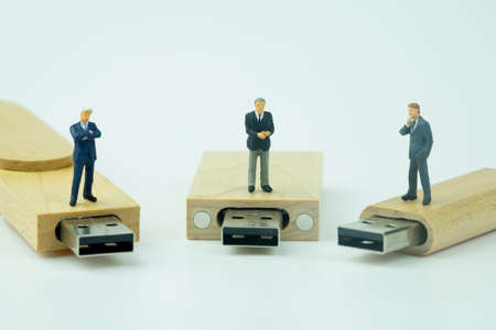 Miniature people businessman standing on wooden USB stick. Analysis or investment Blockchain concept...