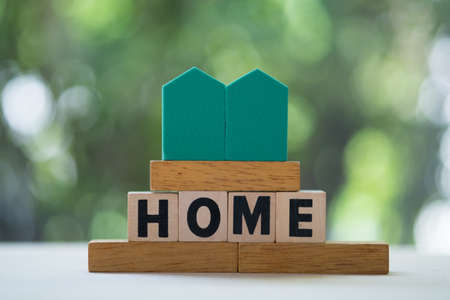 Miniature home and wooden square block or cube on table with text. Depicts a property related business.の写真素材