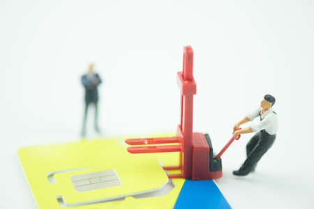 Miniature people moving sim card on with background. Concept of change mobile operatorの写真素材