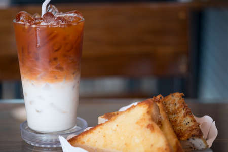 Garlic bread in white paper tray served with Thai milk tea in the breakfastの写真素材
