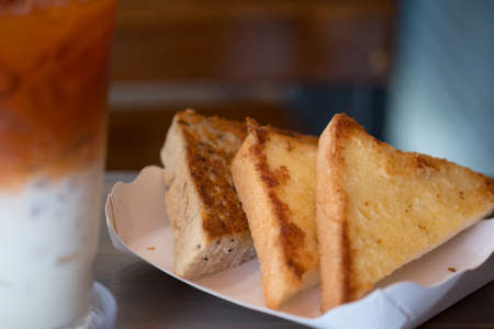Three piece of triangle of garlic bread in white paper trayの写真素材