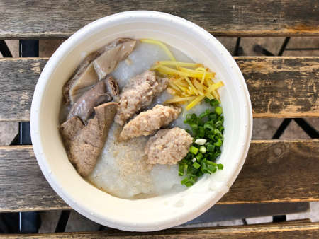 Traditional thai porridge rice gruel in white bowl congee with many toppingの写真素材