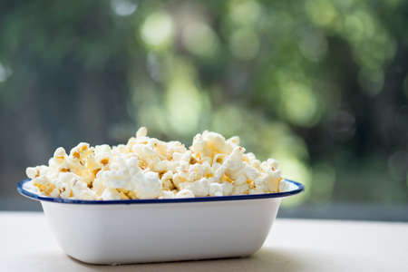 Bowl of salty popcorn with nature background