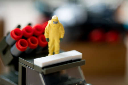 Miniature people crime investigators in hazmat suits stand on army carの写真素材