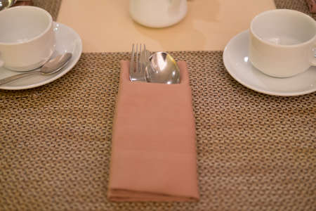 Table set up for dinning room. Spoon and forks in  beige napkinの写真素材