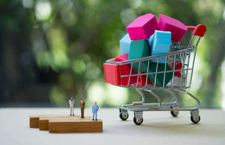 Many house in shopping cart and miniature agent. Buying new house, real estate and home mortgage concept.の写真素材