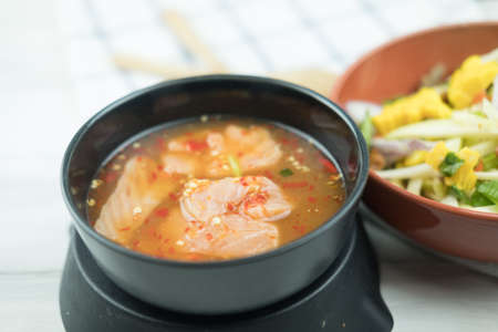 Spicy slice mango salad served with salmon in Thai style sauce in orange bowl. Thai fusion food