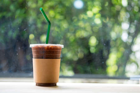 Iced coffee mocha with brown paper sleeve on wood tableの写真素材