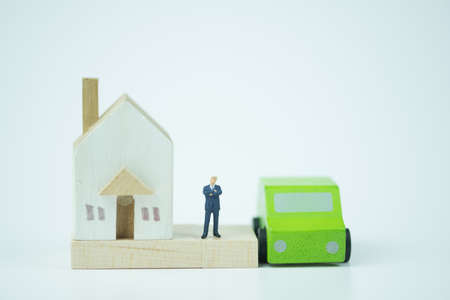 Miniature people : Banker stand with wooden home and wooden car. Concept of buying and selling real...