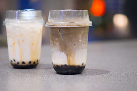 Two plastic cup of Hojicha milk tea and fresh milk and bubble (boba) with layer of cream cheese foam,  Traditional Taiwanese drinkの写真素材