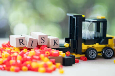 Toy forklift with letter block RISK on problem. Concept of risk assessment for business or investmentの写真素材