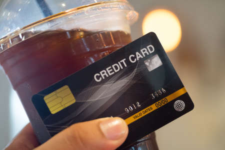 Paying for iced coffee by credit card with blur light background