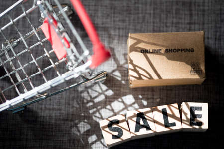 Wooden block in word is SALE and miniature brown box with Shadow shopping cart , shopping online...